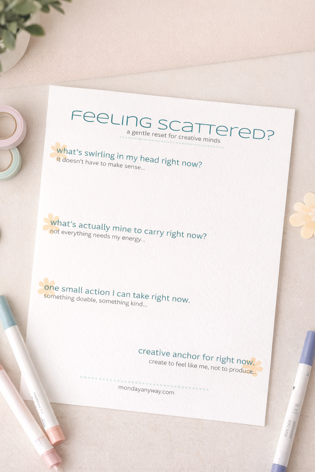 Sheet of paper with 'Feeling Scattered?' text and questions on a light surface with markers and flowers.