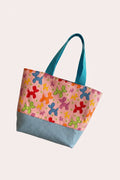 Small tote bag with colorful balloon dog pattern held by a hand against a neutral background