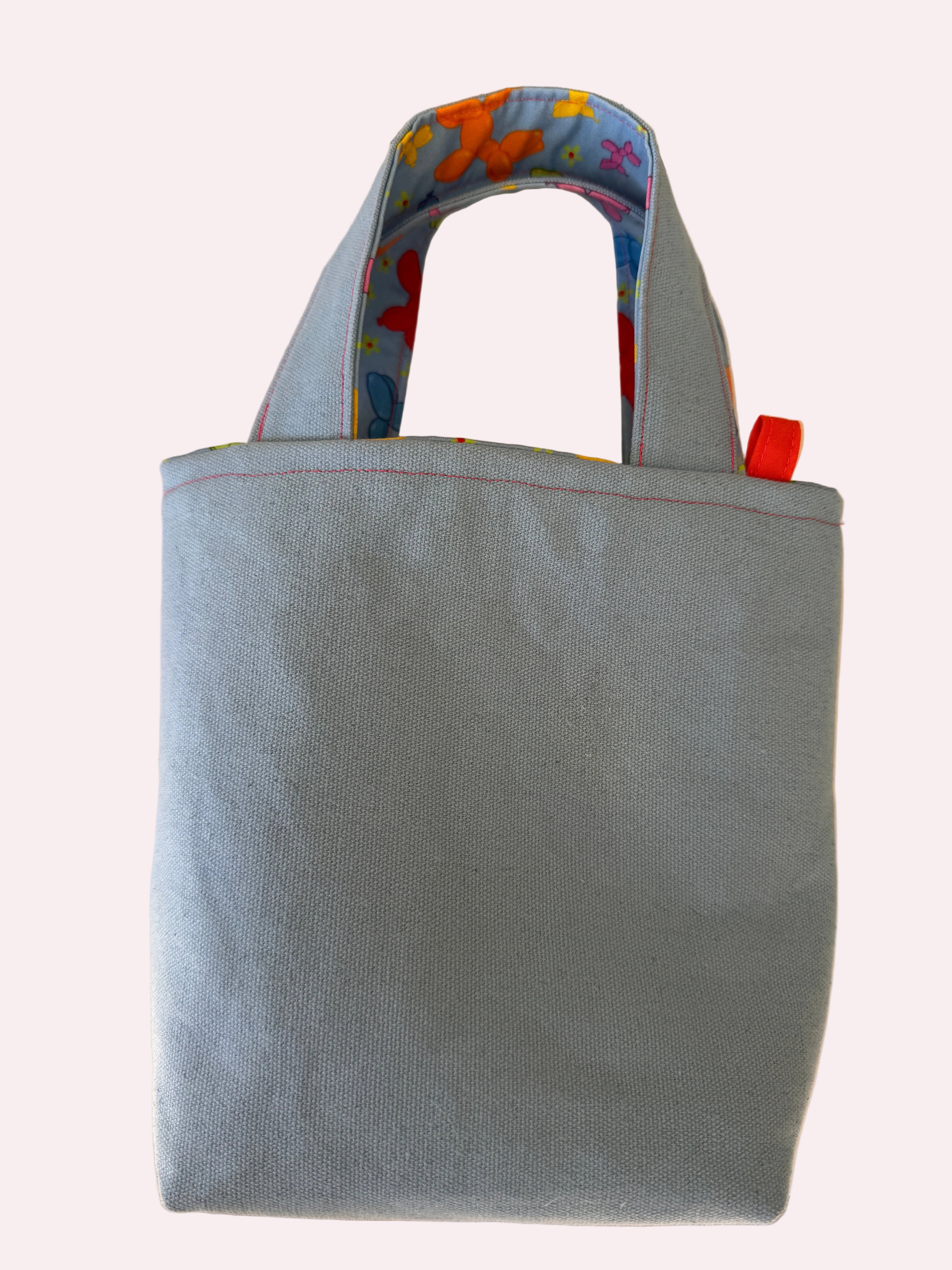 light blue tote bag with colorful handle on a light surface