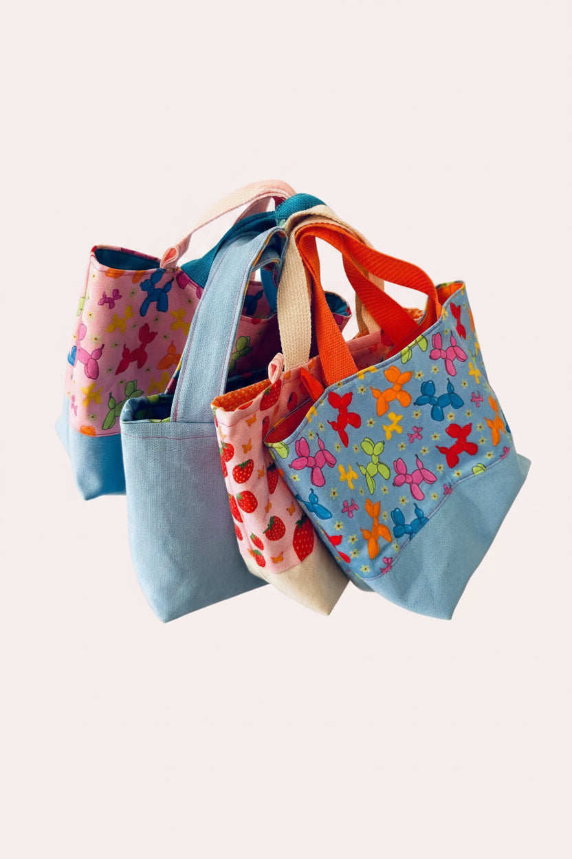 Four colorful fabric bags with various patterns against a pink background