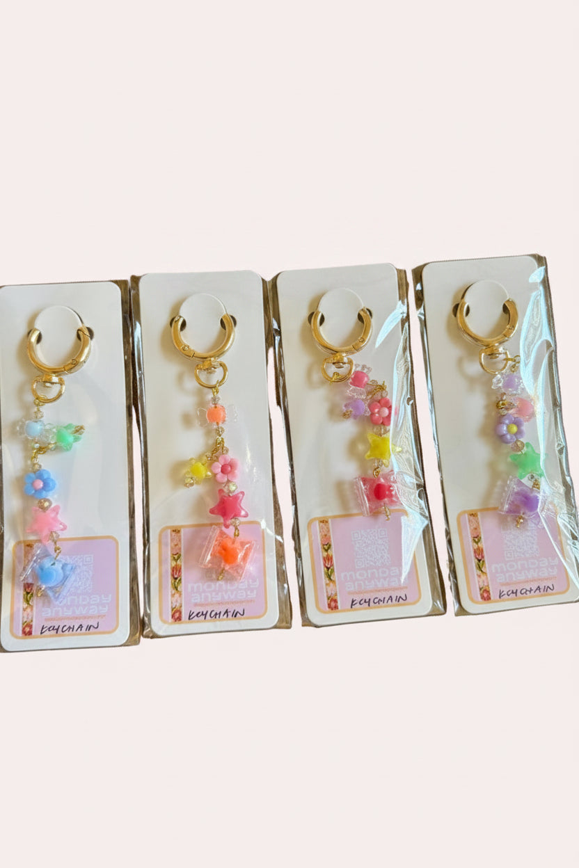 Four pairs of colorful keychains on clear cards against a wooden surface