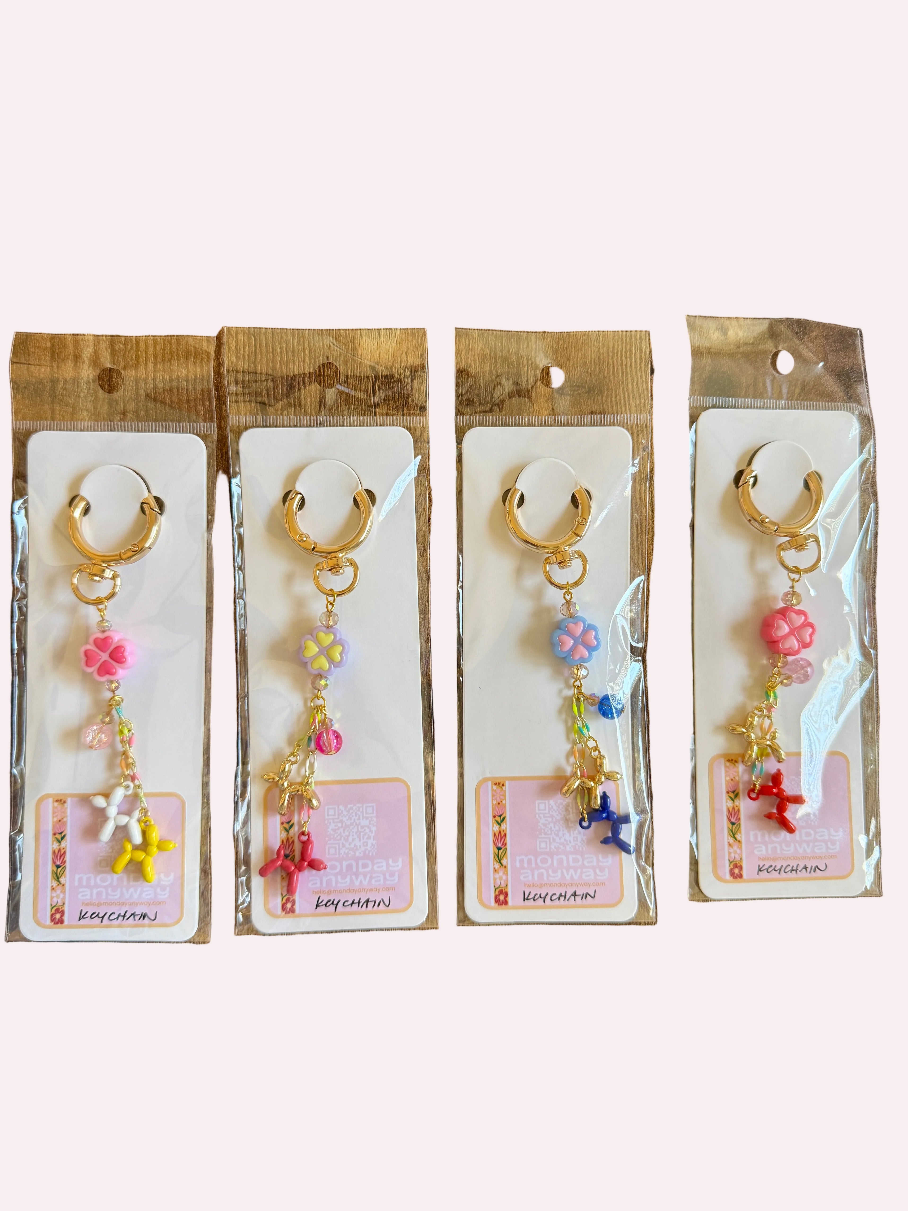 Four pairs of keychains on cards with decorative charms on a wooden surface