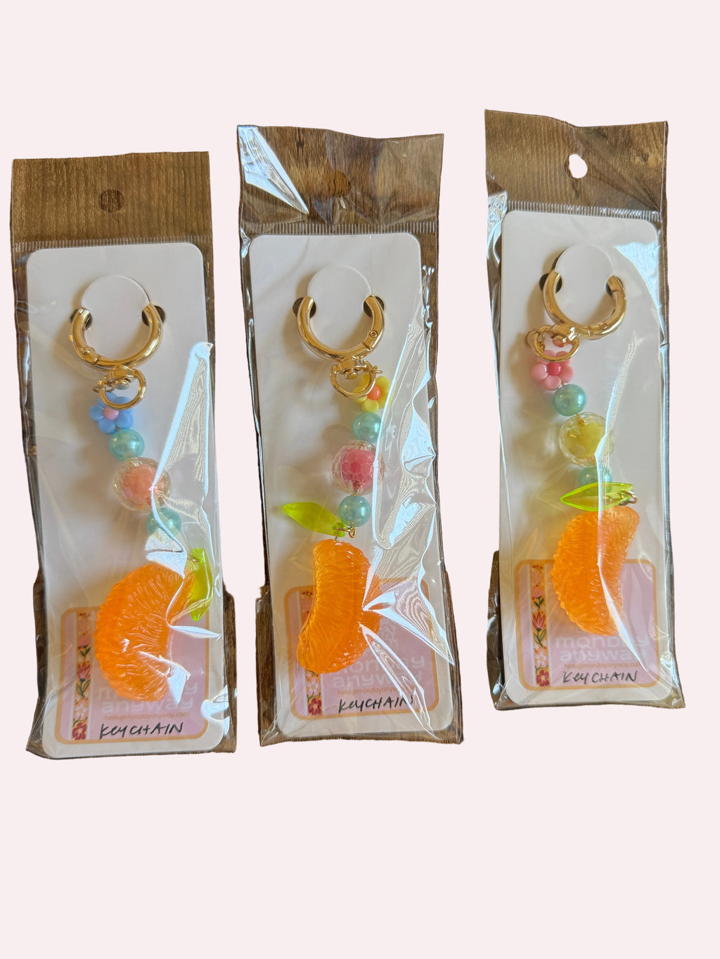 Three identical keychains in clear packaging on a wooden surface