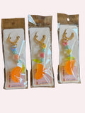 Three identical keychains in clear packaging on a wooden surface