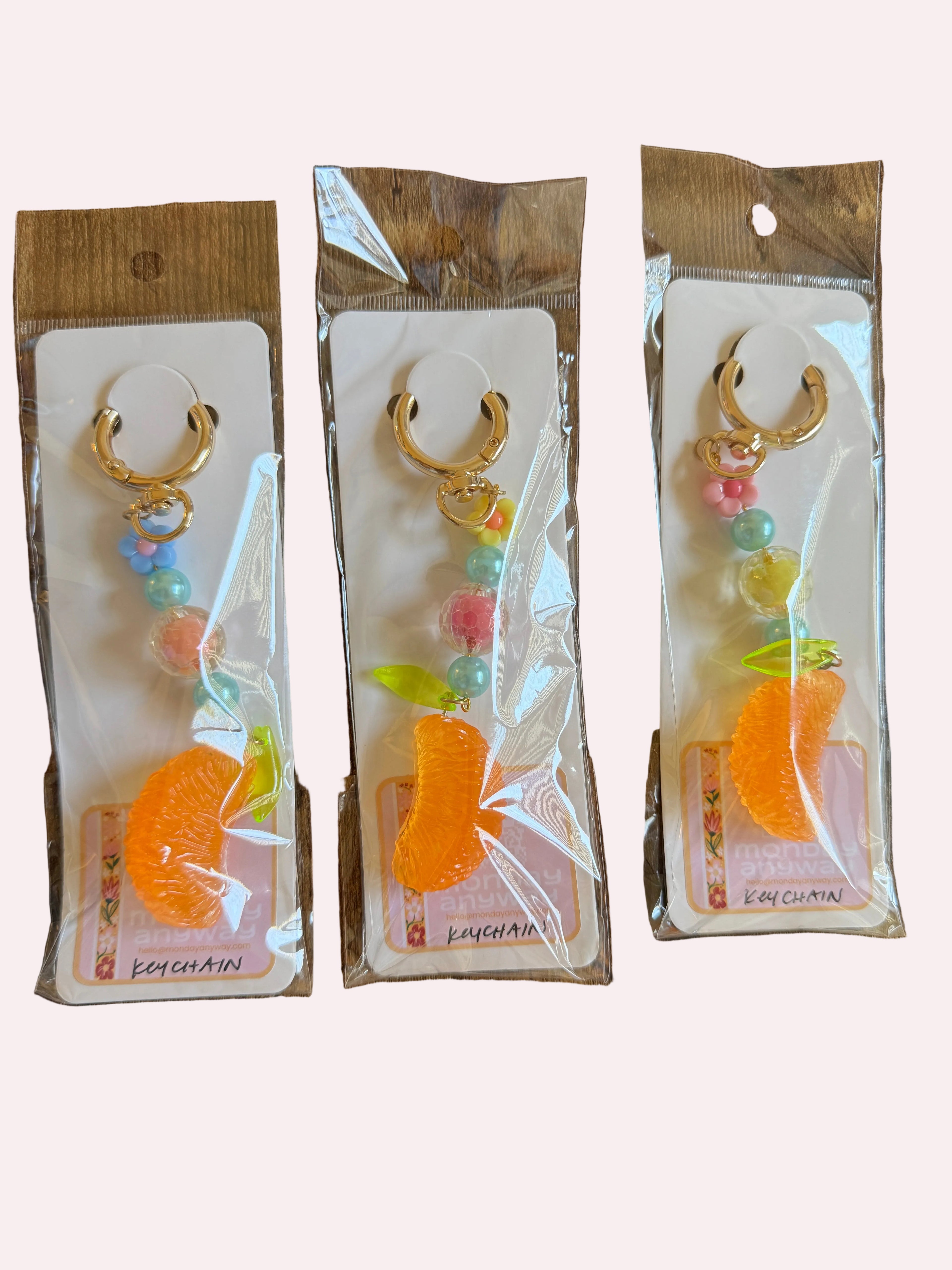 Three identical keychains in clear packaging on a wooden surface